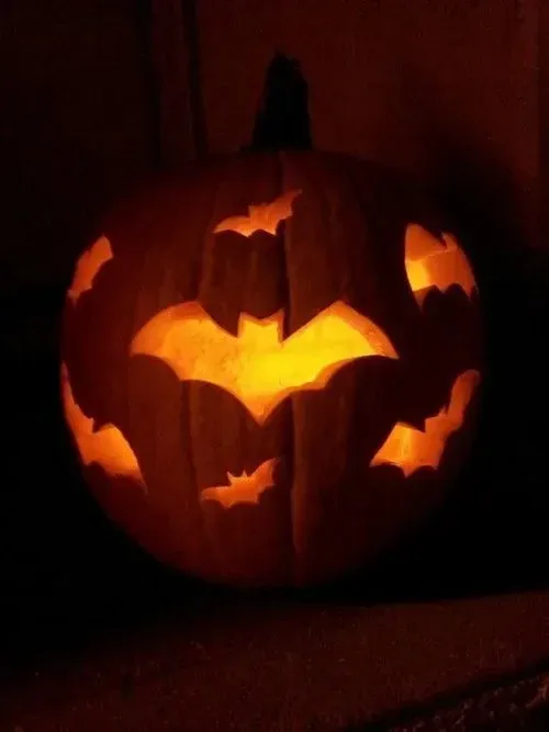 kid friendly pumpkin carving ideas with bat cutouts, glowing pumpkin, and easy Halloween design