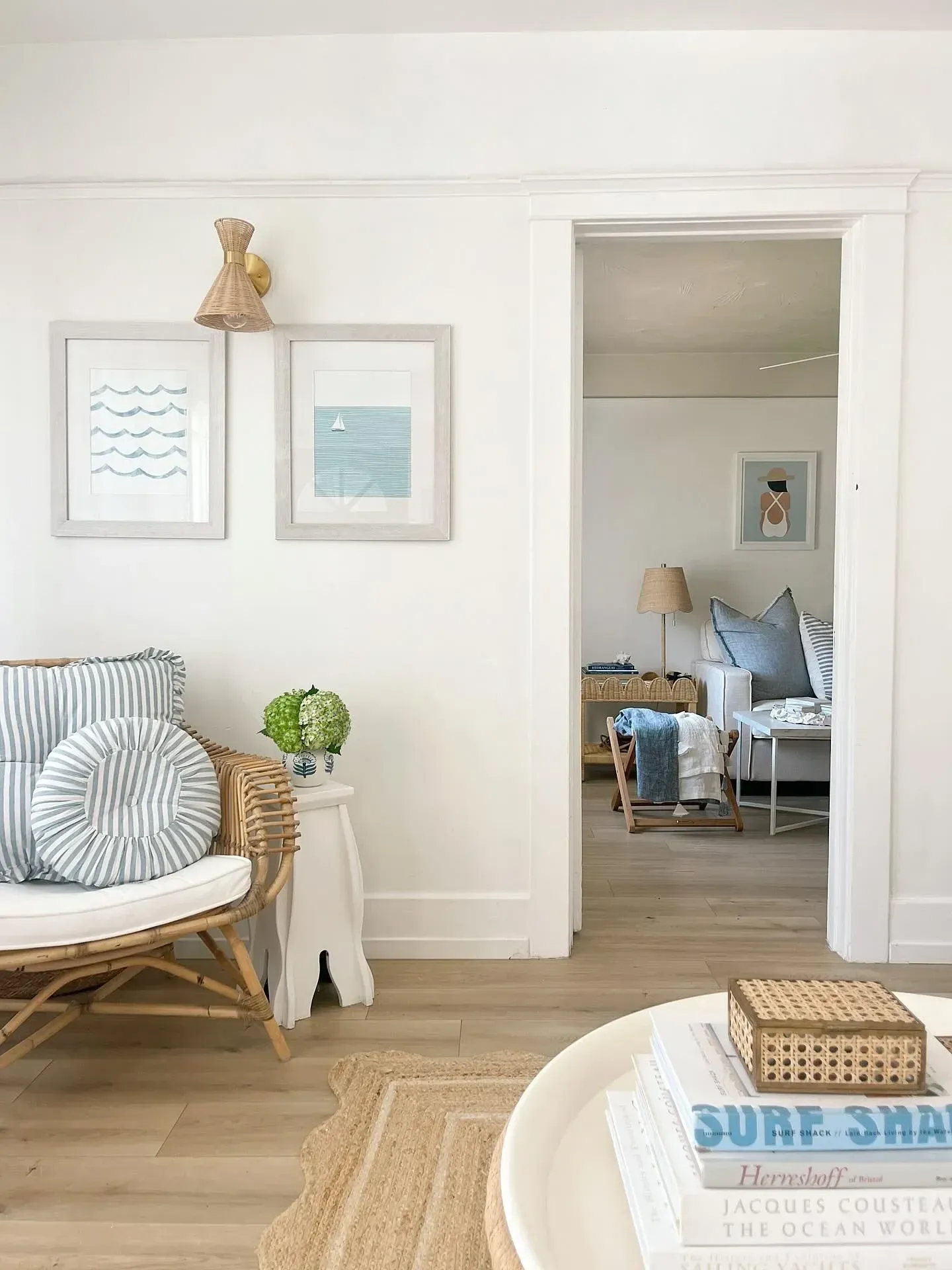 beachy coastal living room ideas with white chair, framed prints, blue pillow, and woven rug