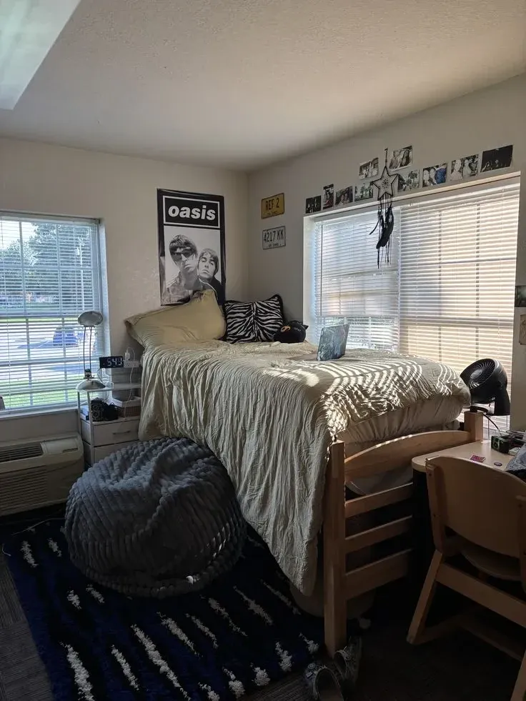 dorm decorating ideas for guys with bean bag chair, lofted bed, desk, sports wall art, and dorm storage