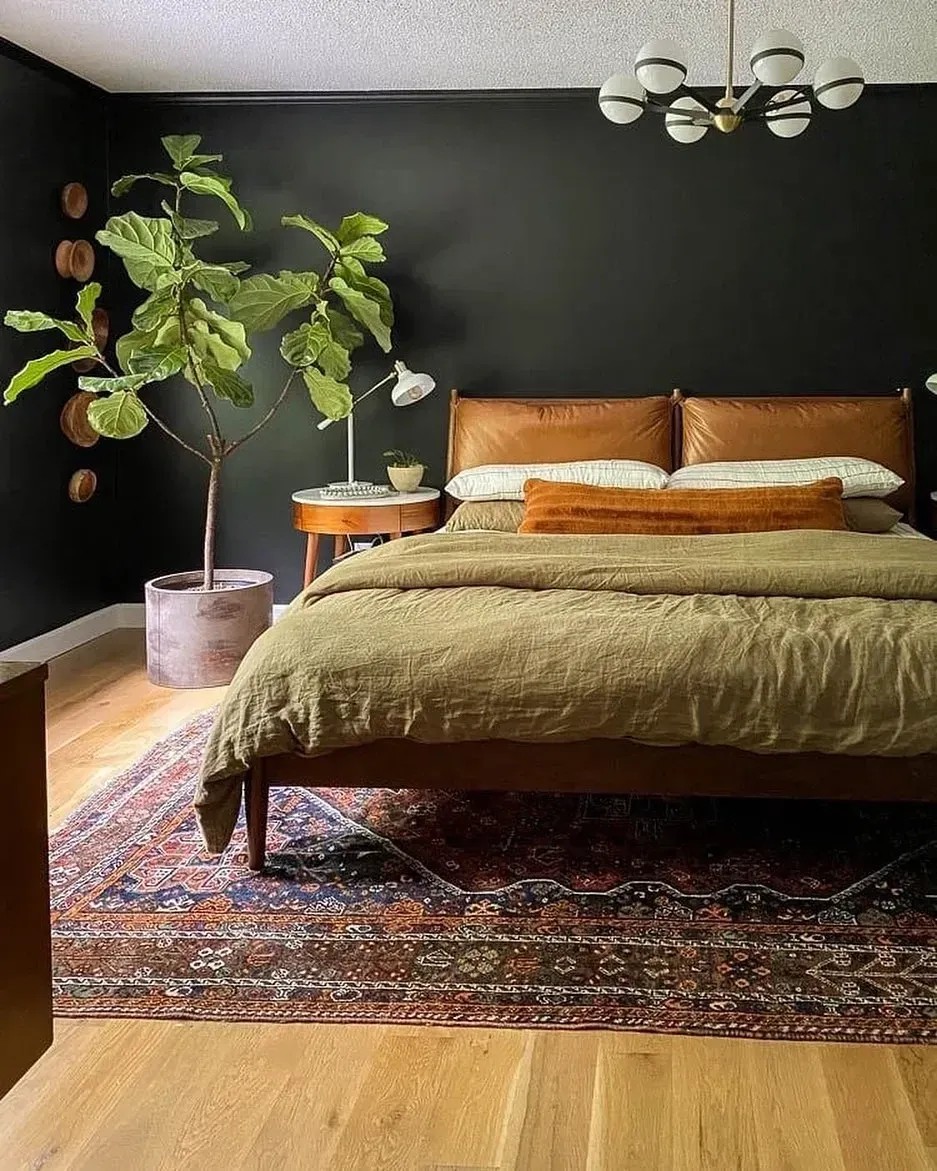 dark boho bedroom ideas with black wall, mustard bedding, plants, vintage rug, and wood furniture
