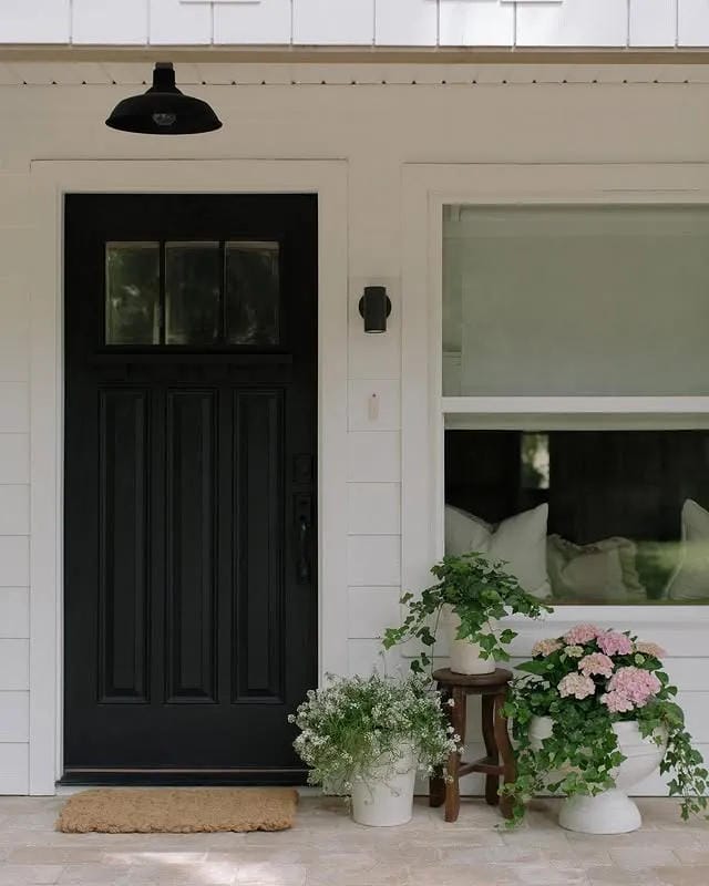 front porch planter idea with black door white flowers pink blooms and trailing greenery