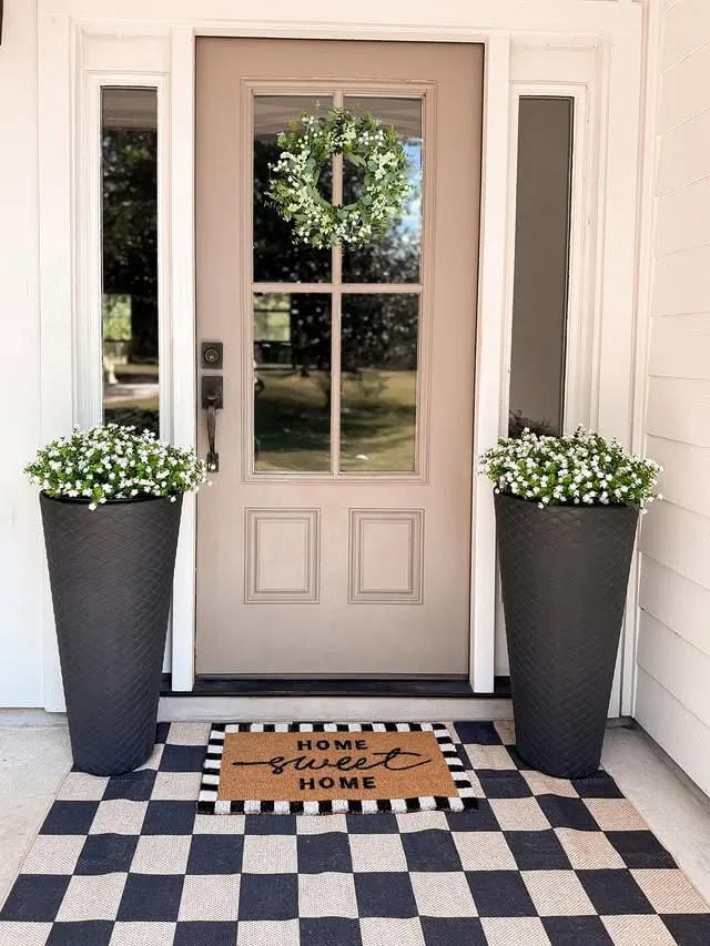 small front porch ideas with tall black planters white flowers wreath and checkered tile