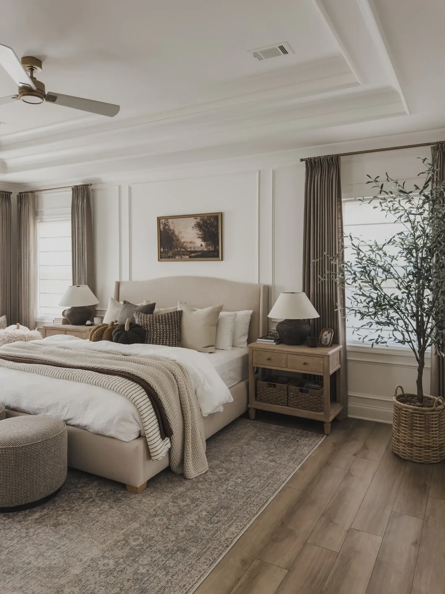fall bedroom ideas with neutral bedding, gray curtains, wood nightstand, potted tree, bench, and soft rug
