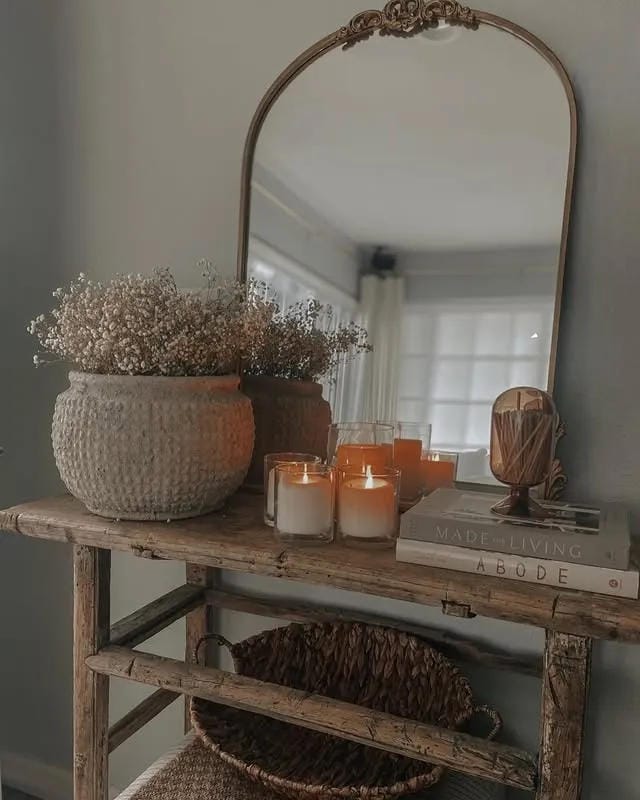 entryway table decor with moody mirror candles dried flowers and woven basket
