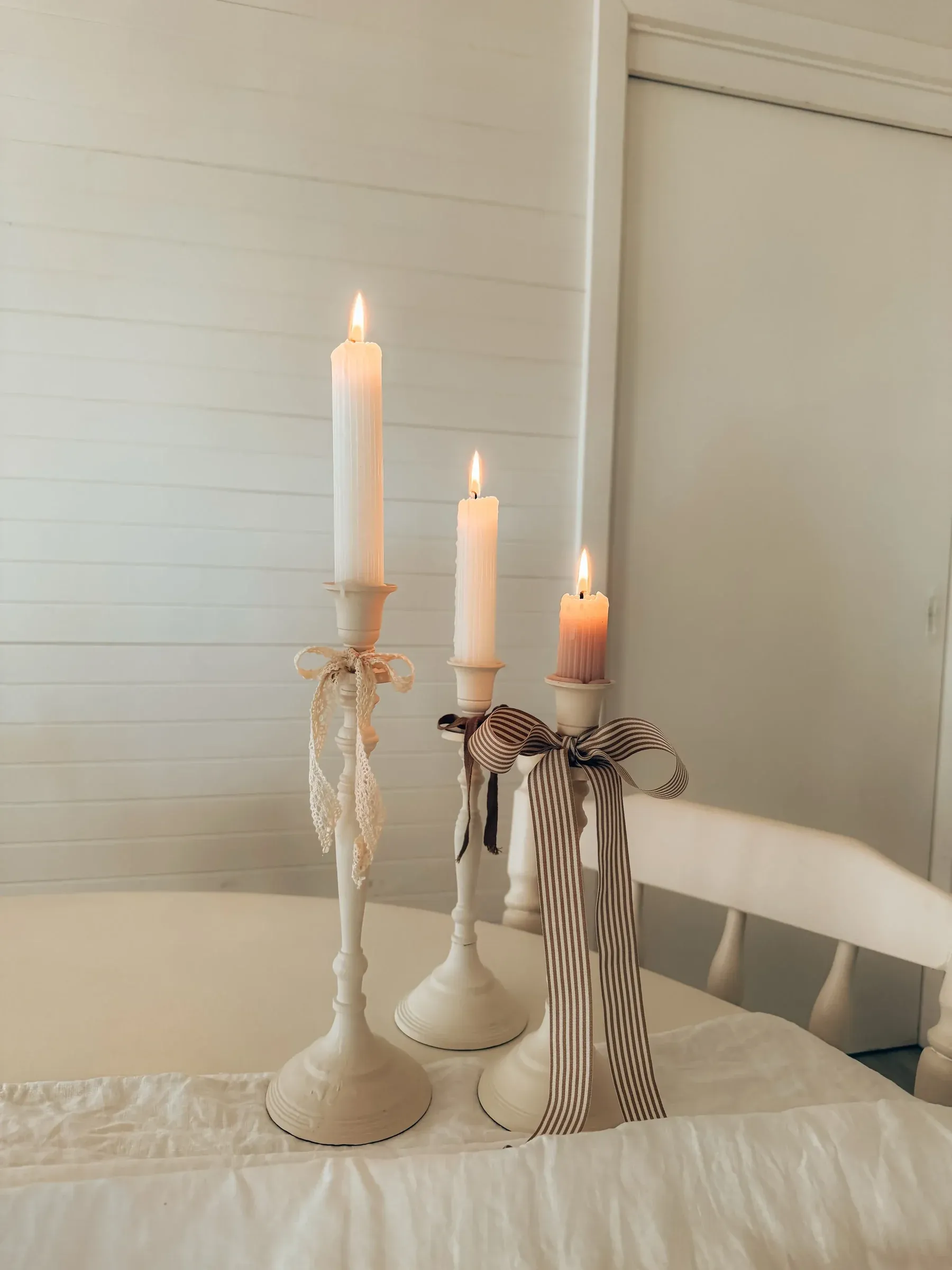 vintage home decor ideas with white candlesticks, taper candles, lace ribbon, and striped bow