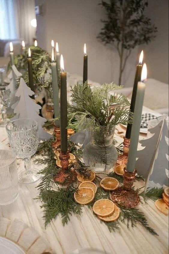 christmas table centerpiece with greenery candles and festive holiday place settings