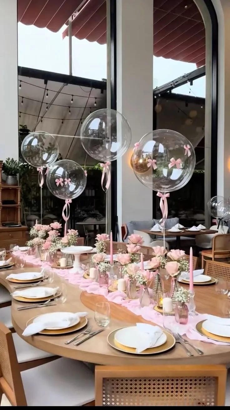 girl baby shower table decor with clear balloons and pink bows