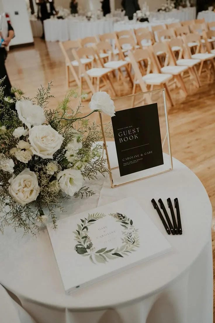 wedding welcome table with guest book sign flowers and pens