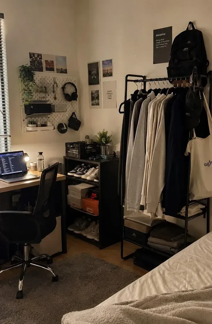 dorm decorating ideas for guys with clothing rack, desk, backpack hooks, plants, and organized dorm room