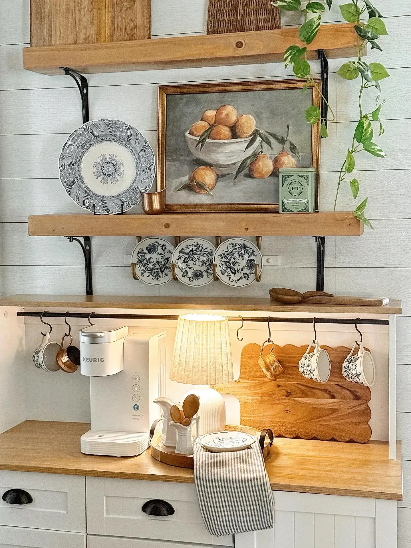 kitchen coffee station ideas with open shelves, mugs, plants, and counter lighting