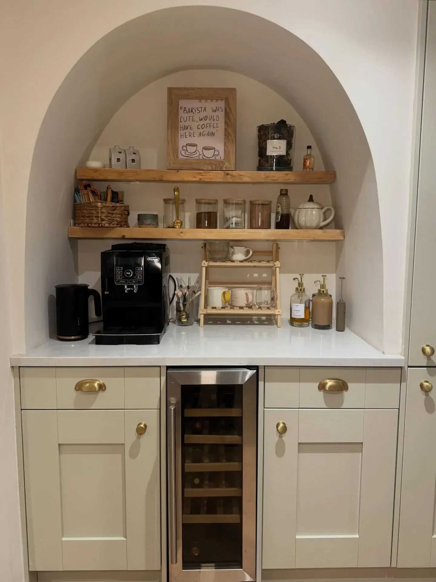 coffee station ideas with arched nook, wooden shelves, cute coffee print, mugs, syrups, and coffee machine