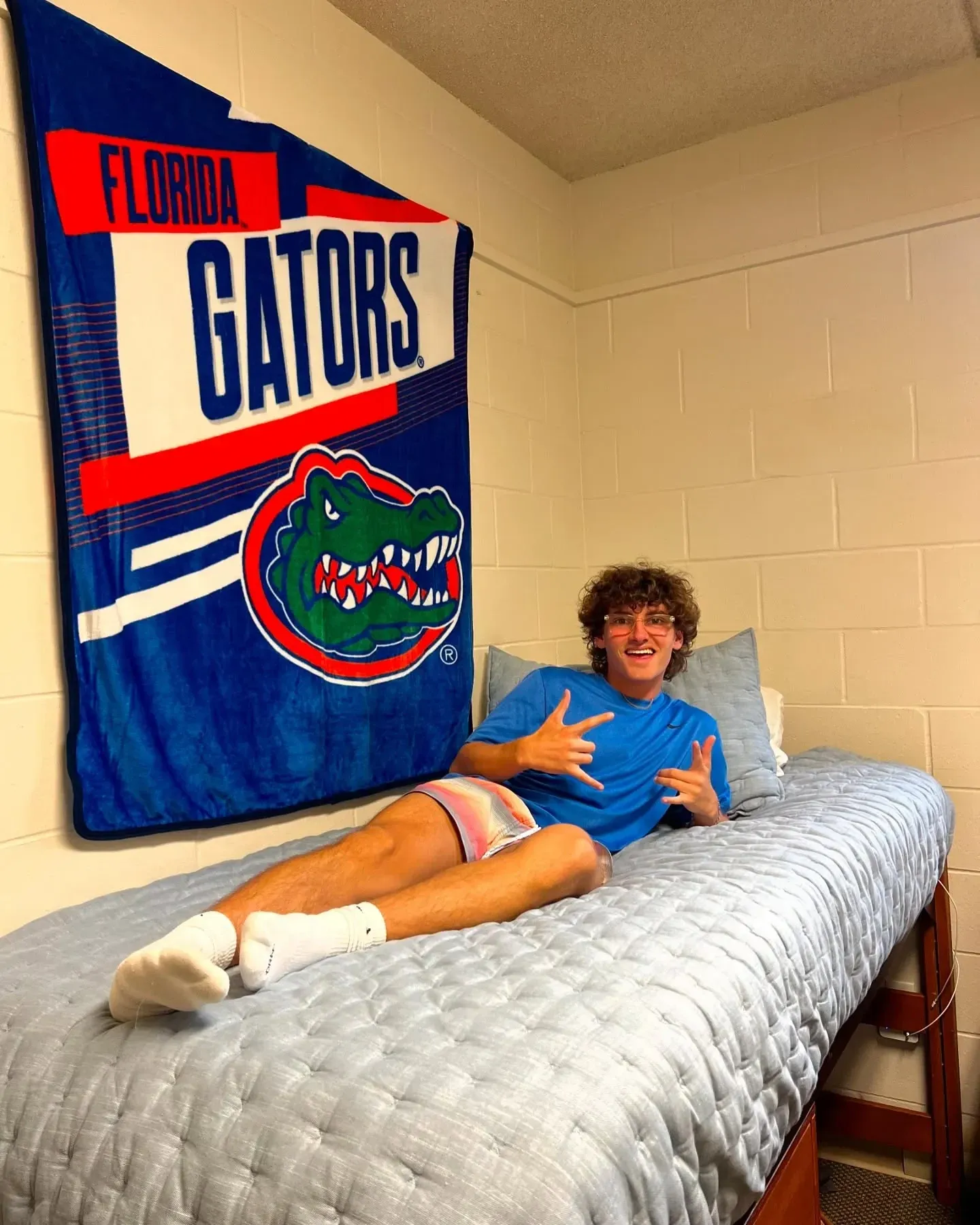 dorm decorating ideas for guys with college flag above bed, simple bedding, and dorm wall decor