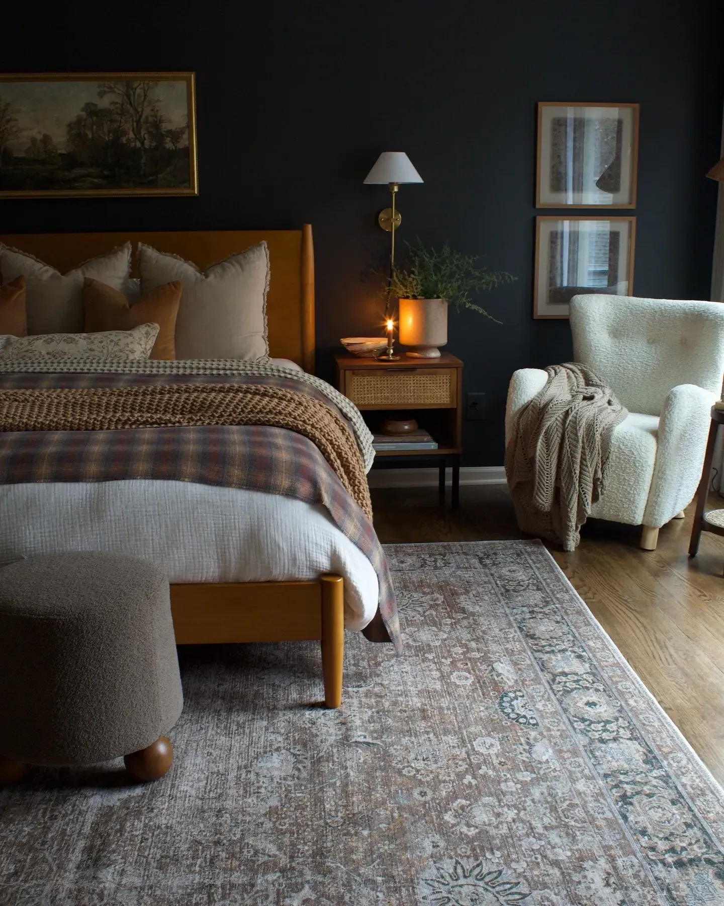 dark boho bedroom ideas with dark wall, plaid bedding, warm lamp, vintage art, and cozy chair