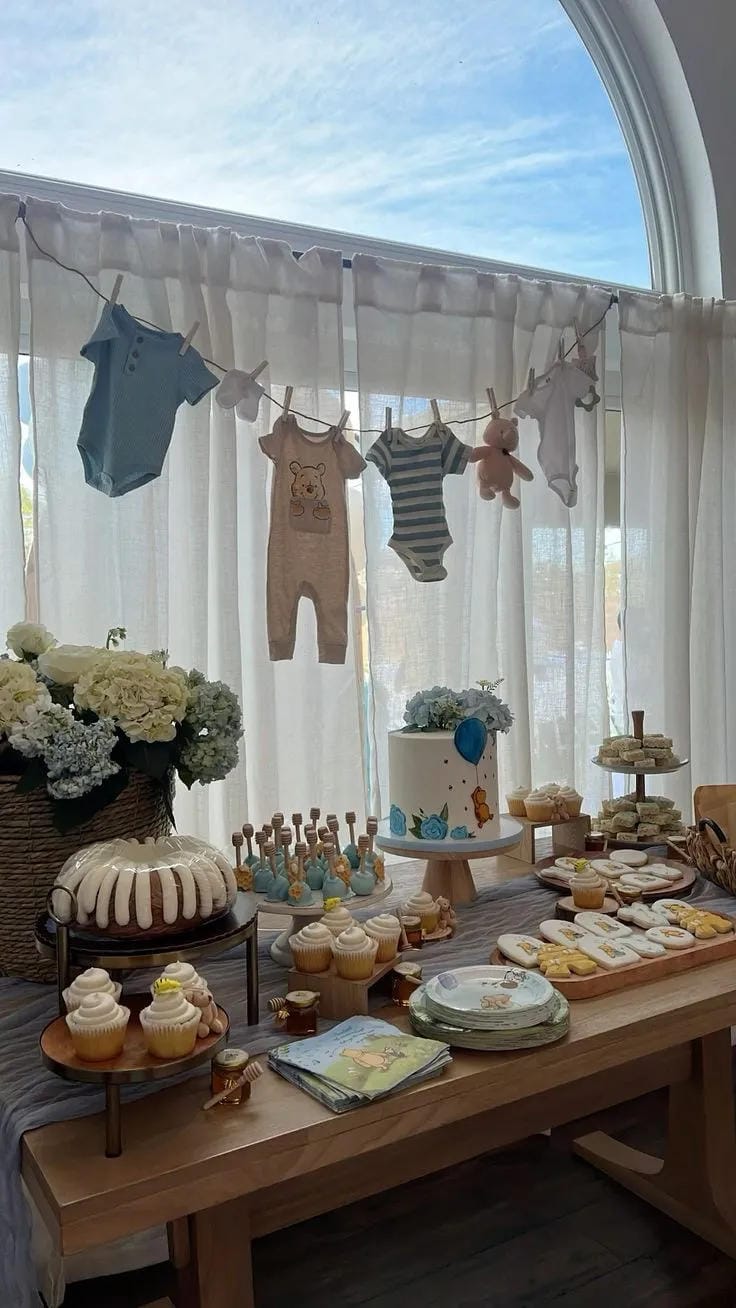 boy baby shower dessert table with hanging baby clothes
