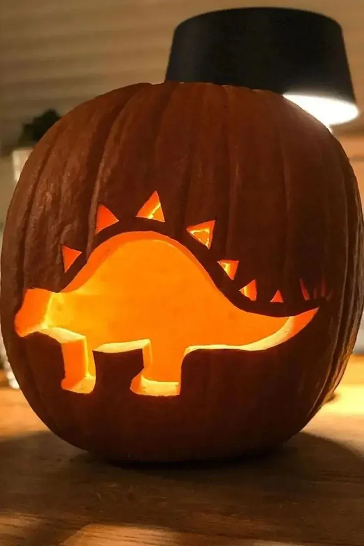 kid friendly pumpkin carving ideas with dinosaur silhouette pumpkin carving and glowing cutout
