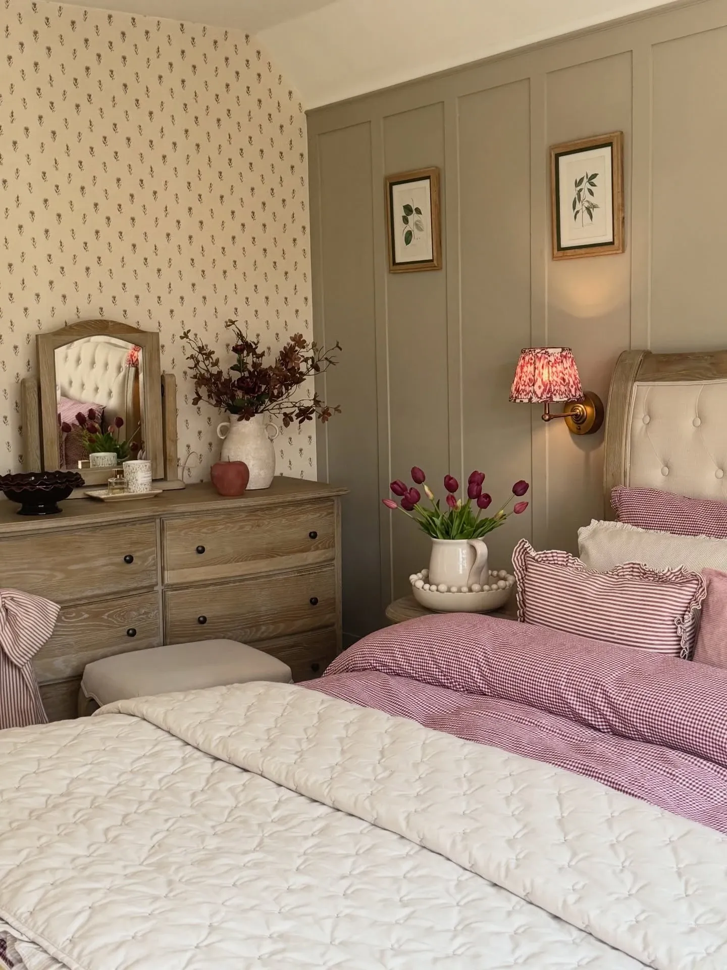 fall bedroom ideas with dusty pink bedding, floral decor, warm lamp, dresser styling, and soft fall bedroom colors