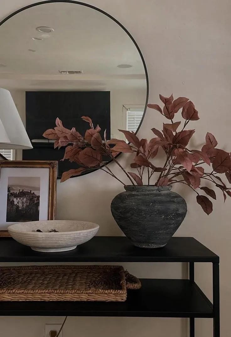 fall entryway table decor ideas with grouped fall tray, dark leaves, candle, pumpkins, mirror, and black console table