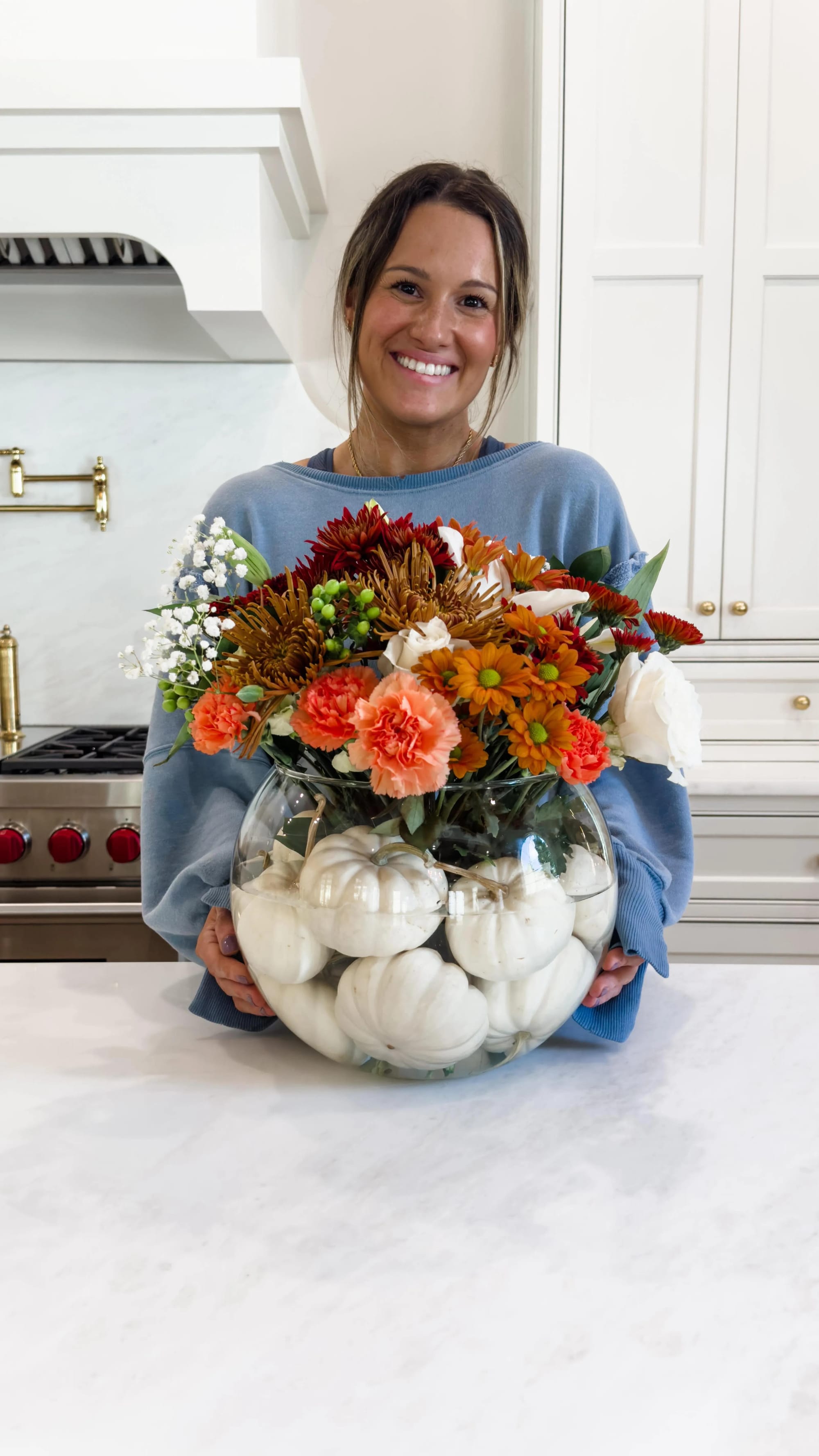 fall flower arrangement ideas with a pumpkin filled with orange flowers and greenery