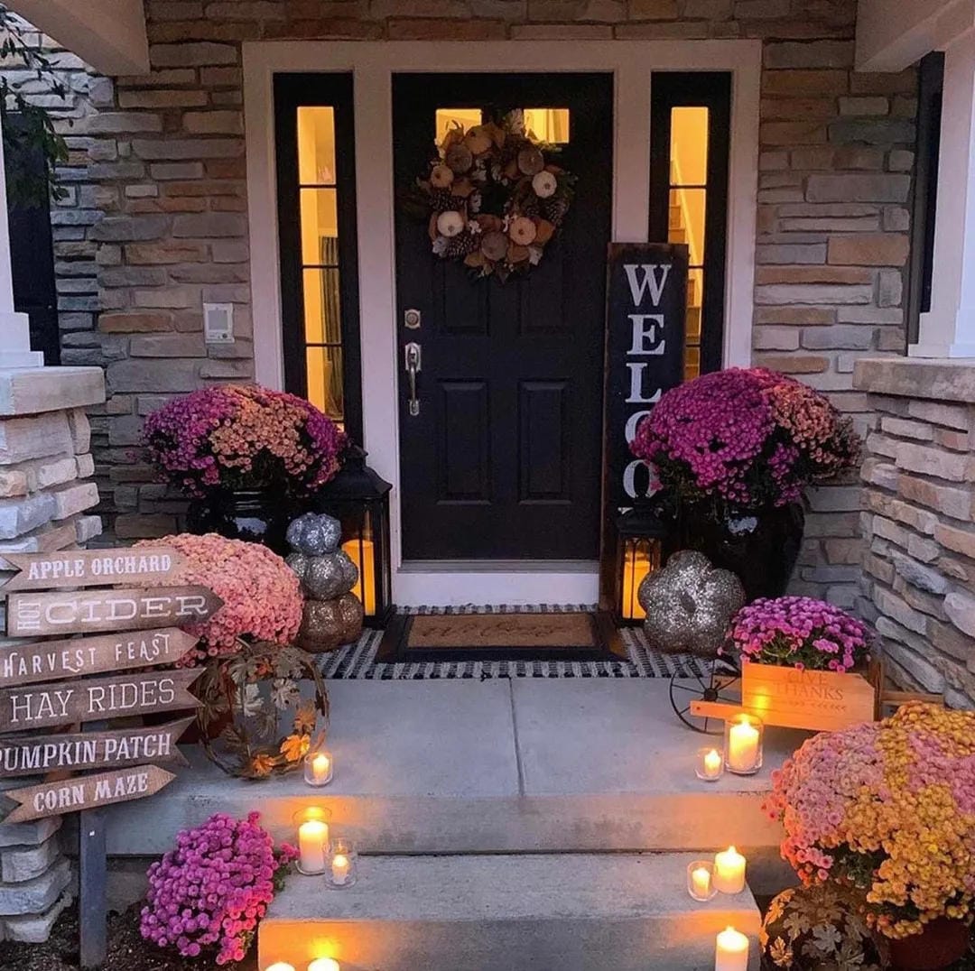 fall front door decor ideas with candles on steps, fall flowers, pumpkins, crates, and welcome sign