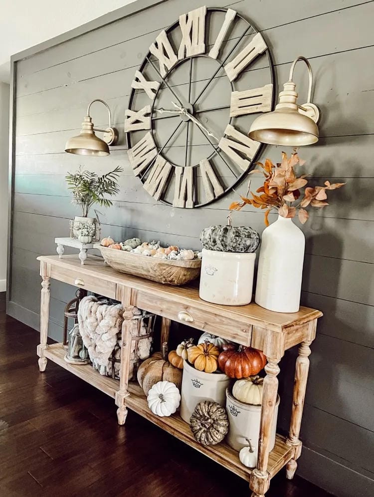 fall entryway table decor ideas with gold mirror, white console table, pumpkins, flowers, baskets, and candle