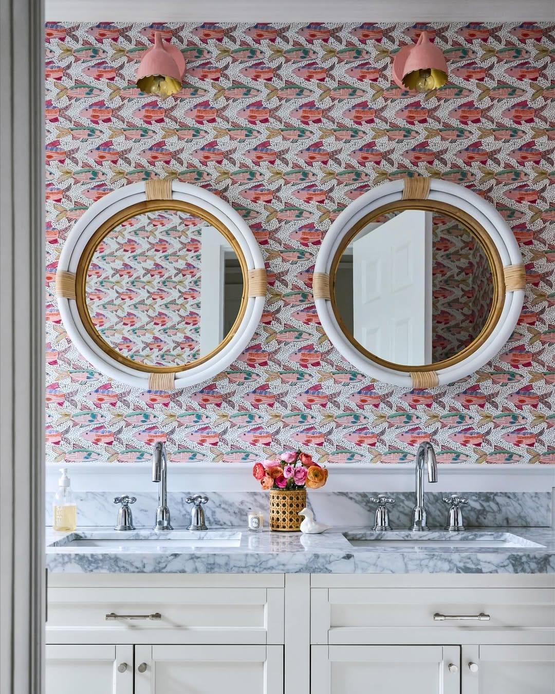 bright bathroom decor with colorful floral wallpaper round mirrors and brass sconces