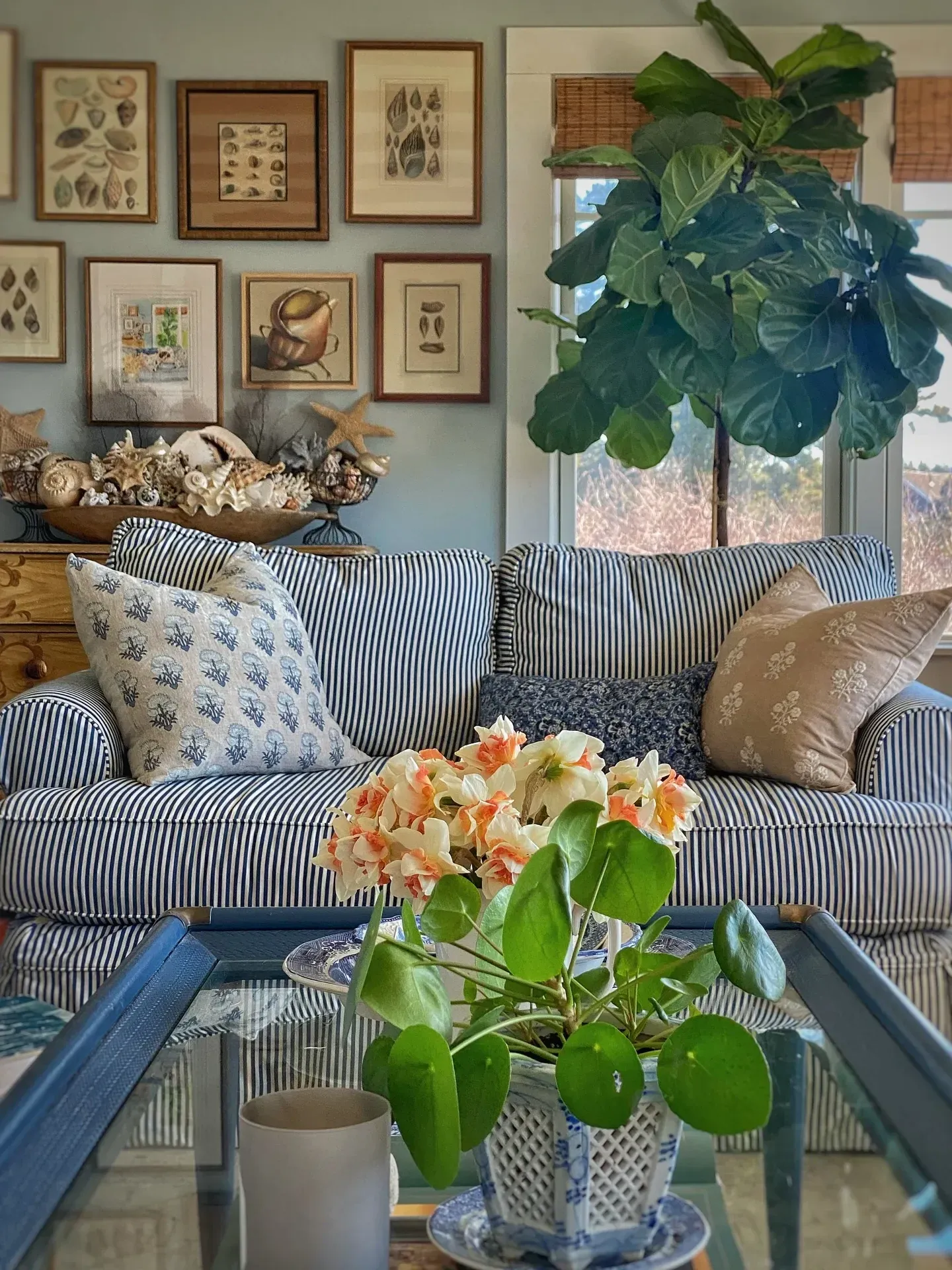 light and airy coastal living room ideas with gallery wall, blue sofa, flowers, and wood table