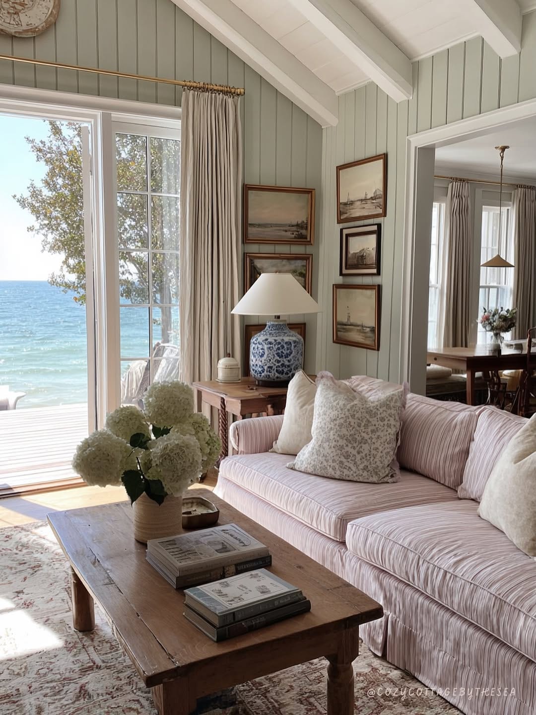 coastal living room ideas with sage paneling, framed art, curtains, and a table lamp