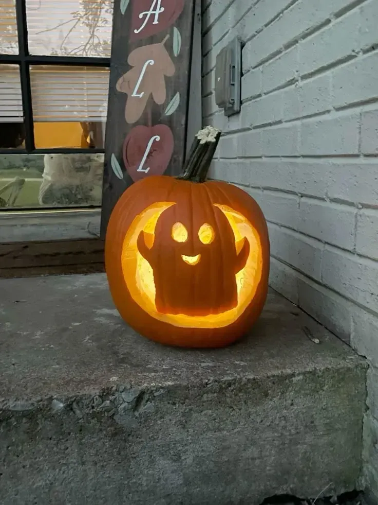 kid friendly pumpkin carving ideas with happy ghost face, glowing eyes, and simple pumpkin design