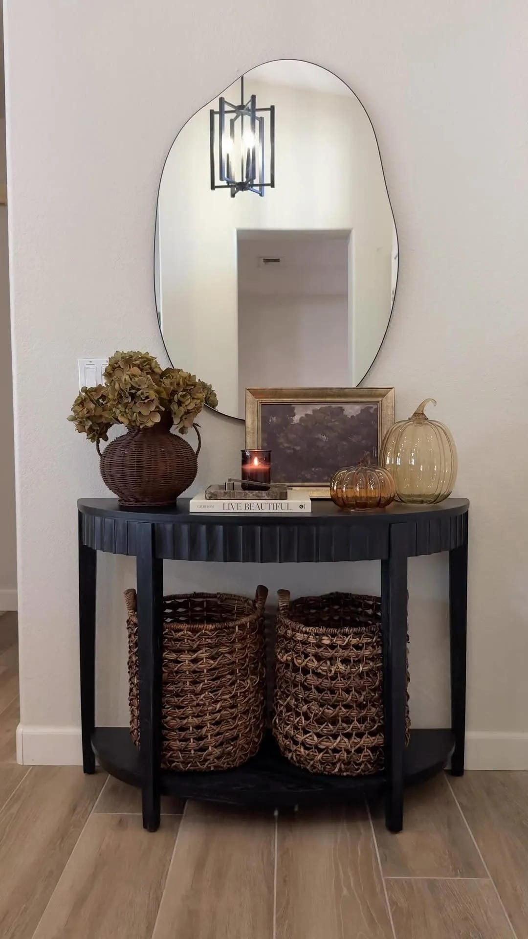 fall entryway table decor ideas with black console, candlelight, mirror, basket, and small fall arrangement