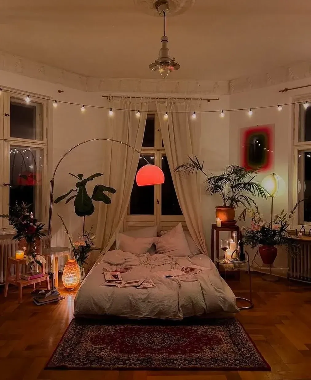 dark boho bedroom ideas with hanging plants, low bed, warm lamp, arched floor light, and layered rug