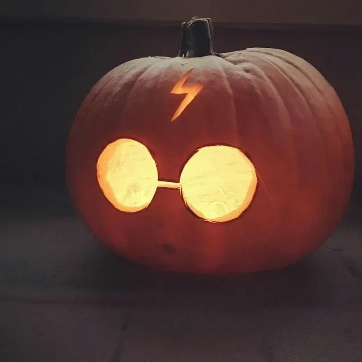 kid friendly pumpkin carving ideas with Harry Potter pumpkin, round glasses, lightning scar, and glowing eyes