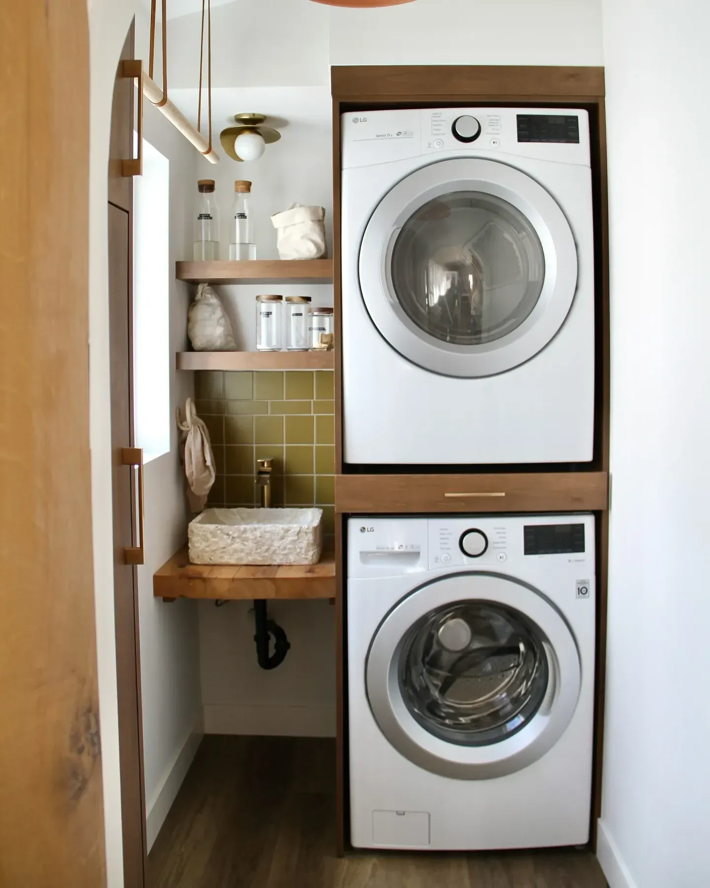 small laundry room ideas with stacked washer dryer, small sink, wood shelf, green tile, and compact laundry closet