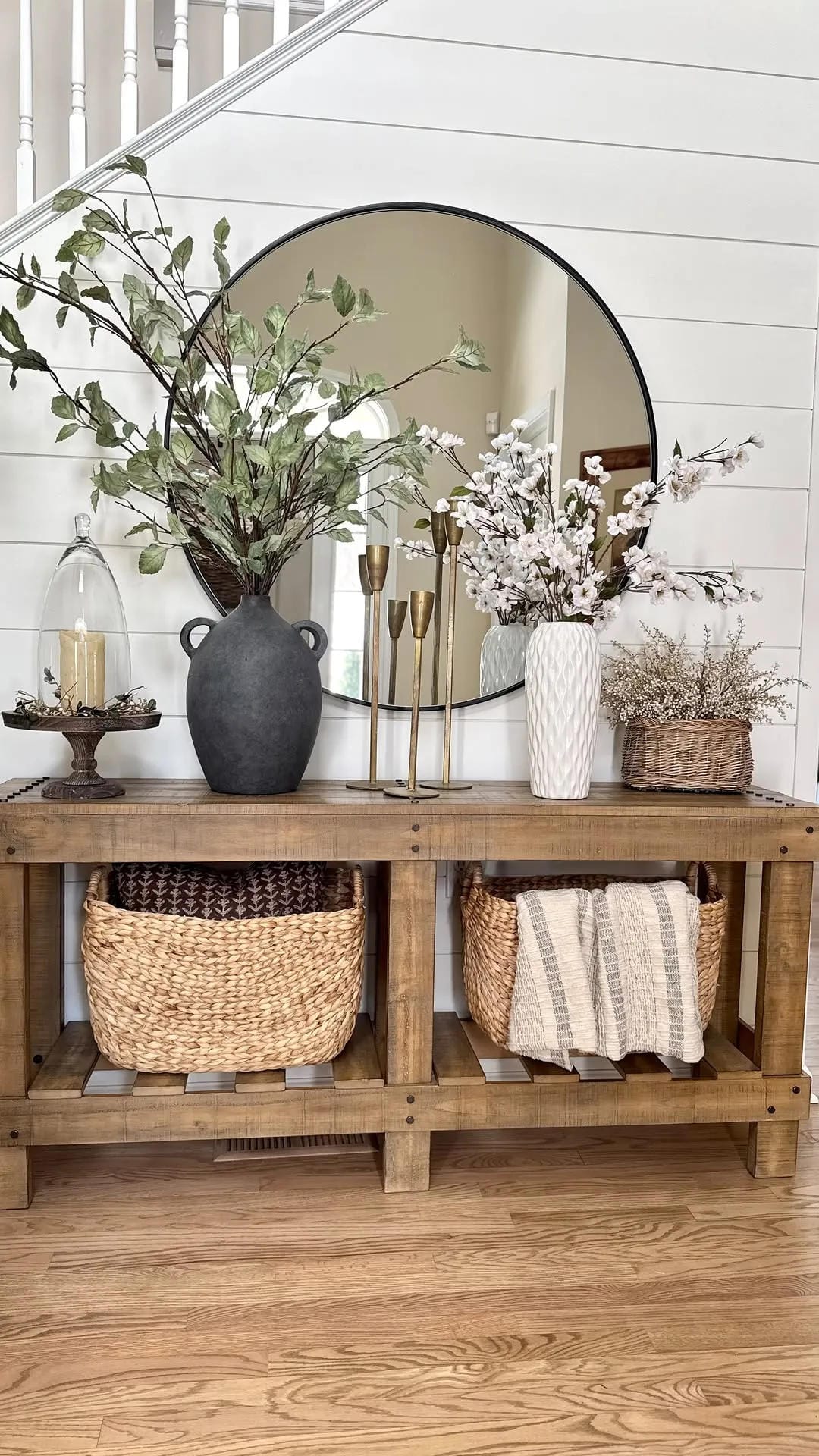 fall entryway table decor ideas with white pumpkins, wood console, round mirror, branches, woven baskets, and neutral decor