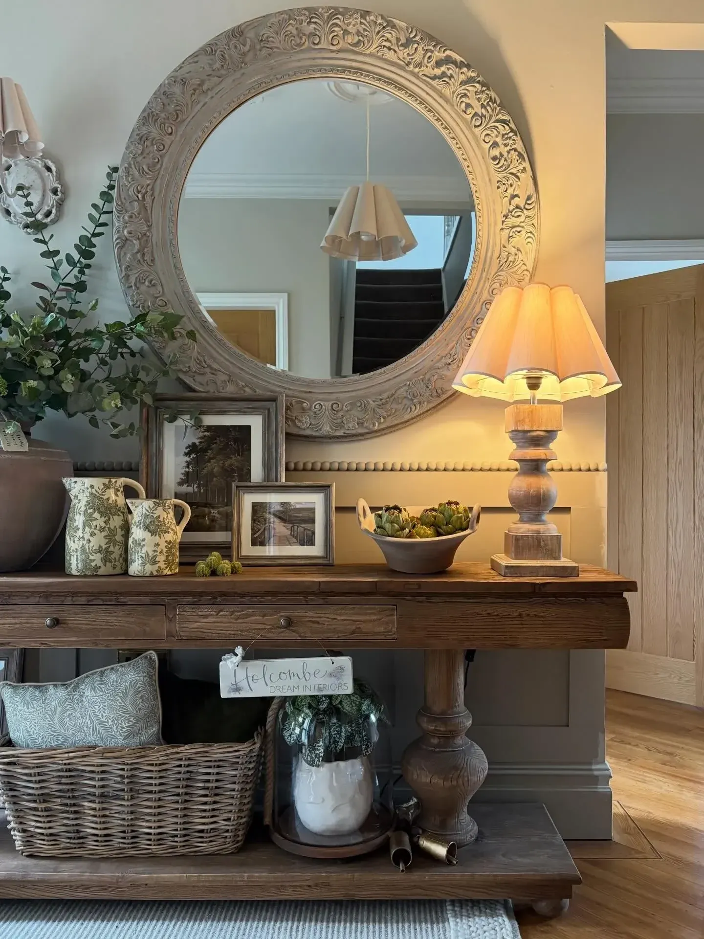 collected vintage home decor ideas with round mirror, framed photos, lamp, and wood console