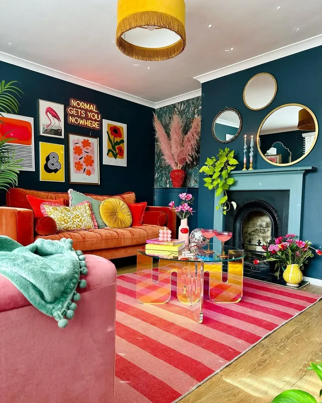 colorful living room ideas with striped pink rug, orange sofa, teal walls, gallery art, and round mirror
