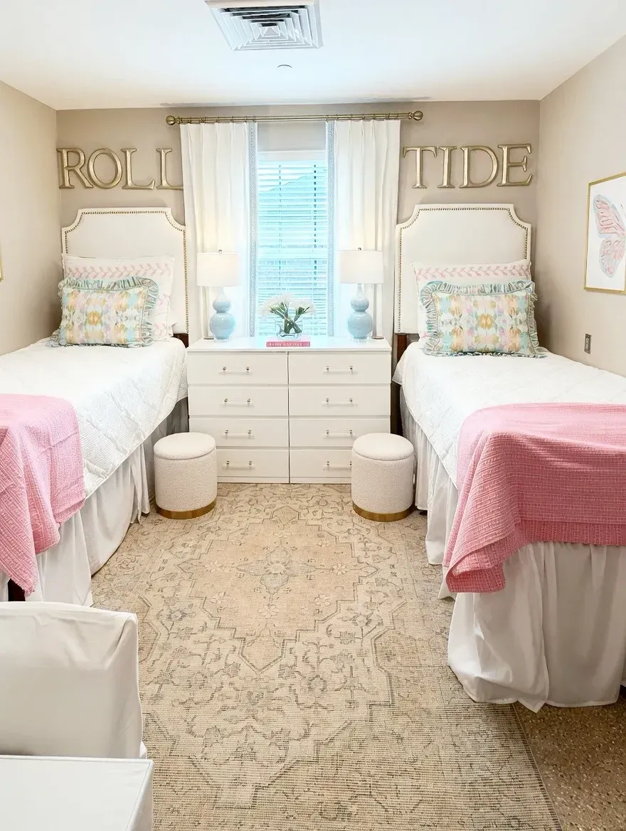 pink and blue dorm room ideas with matching twin beds, pink throws, blue pillows, white bedding, stools, and letter wall decor