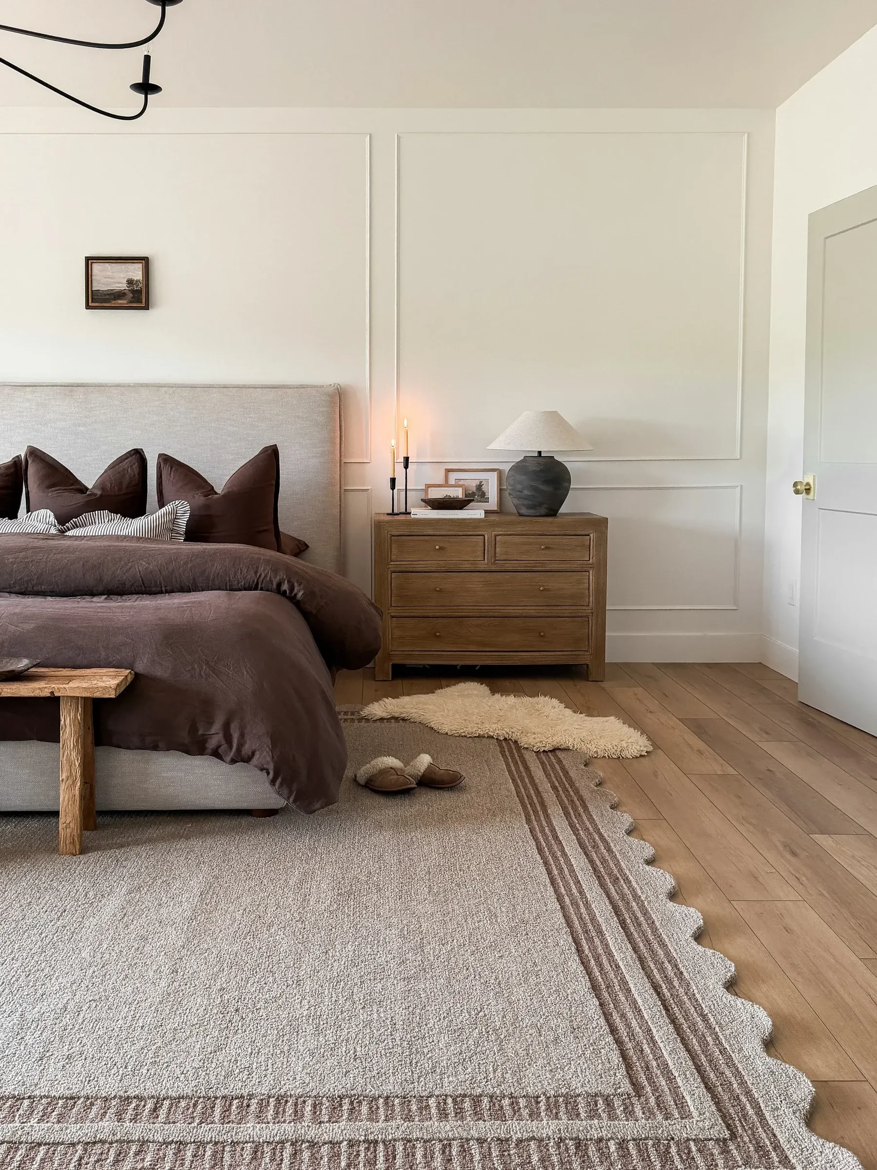 dark boho bedroom ideas with muted bedding, wood nightstand, simple art, soft rug, and minimal boho decor