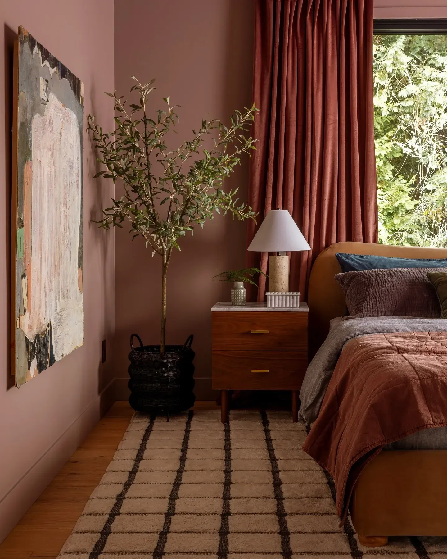 moody bedroom ideas with muted rose walls, rust curtains, wood nightstand, and burgundy bedding