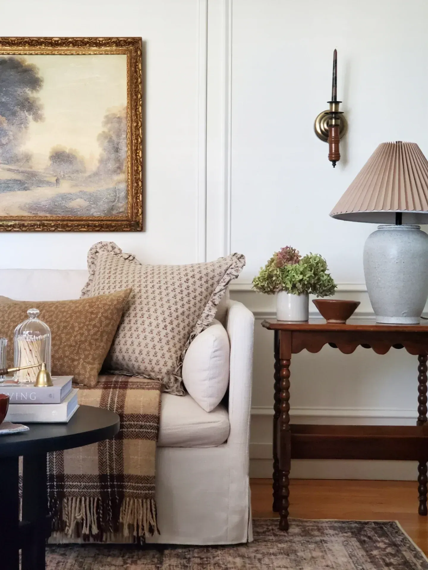 cozy vintage home decor ideas with neutral sofa, wood side table, lamp, and landscape art