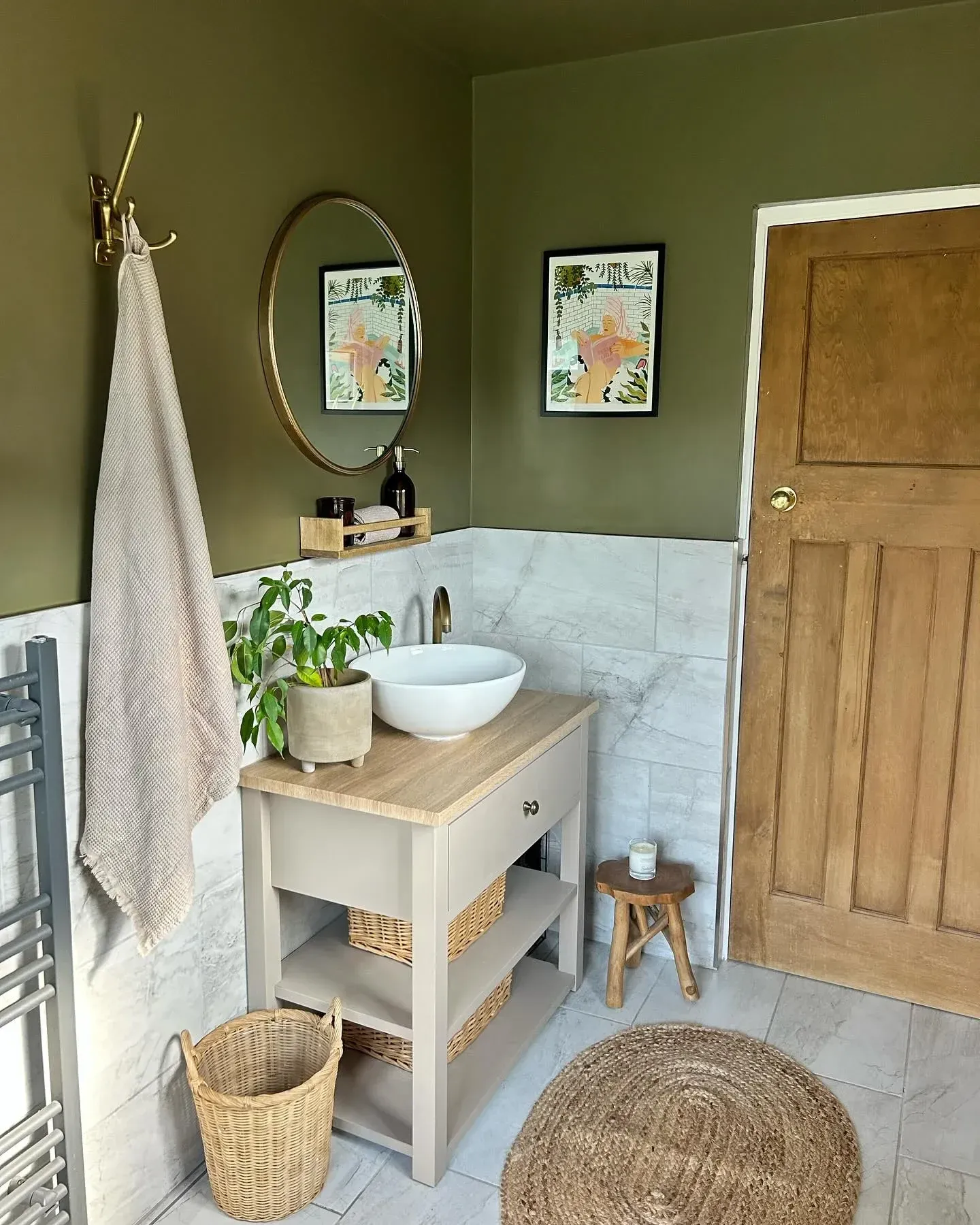 green bathroom ideas with olive walls, wood vanity, round mirror, white tile, and woven rug