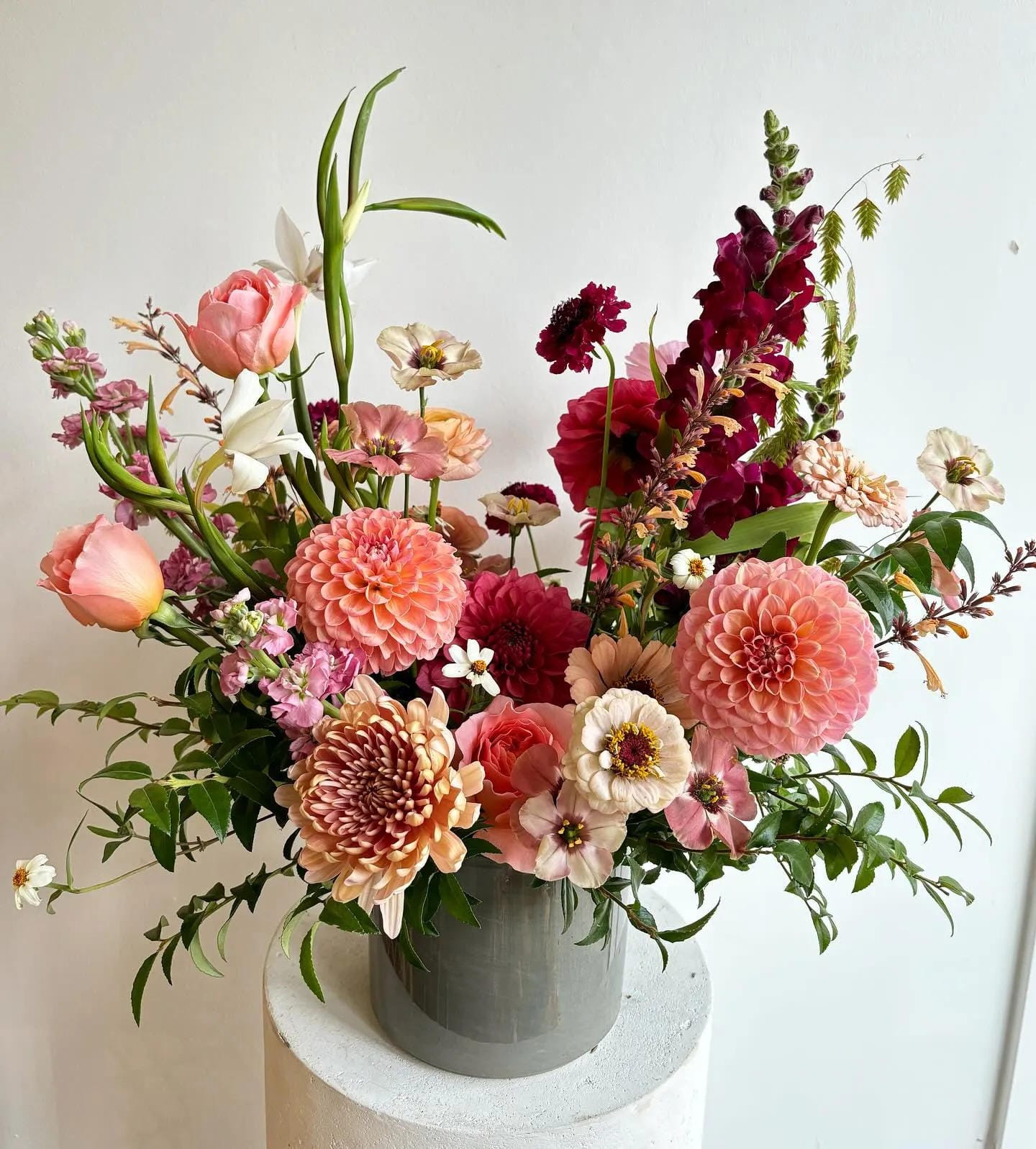 fall flower arrangement ideas with peach dahlias burgundy flowers and greenery in a white vase