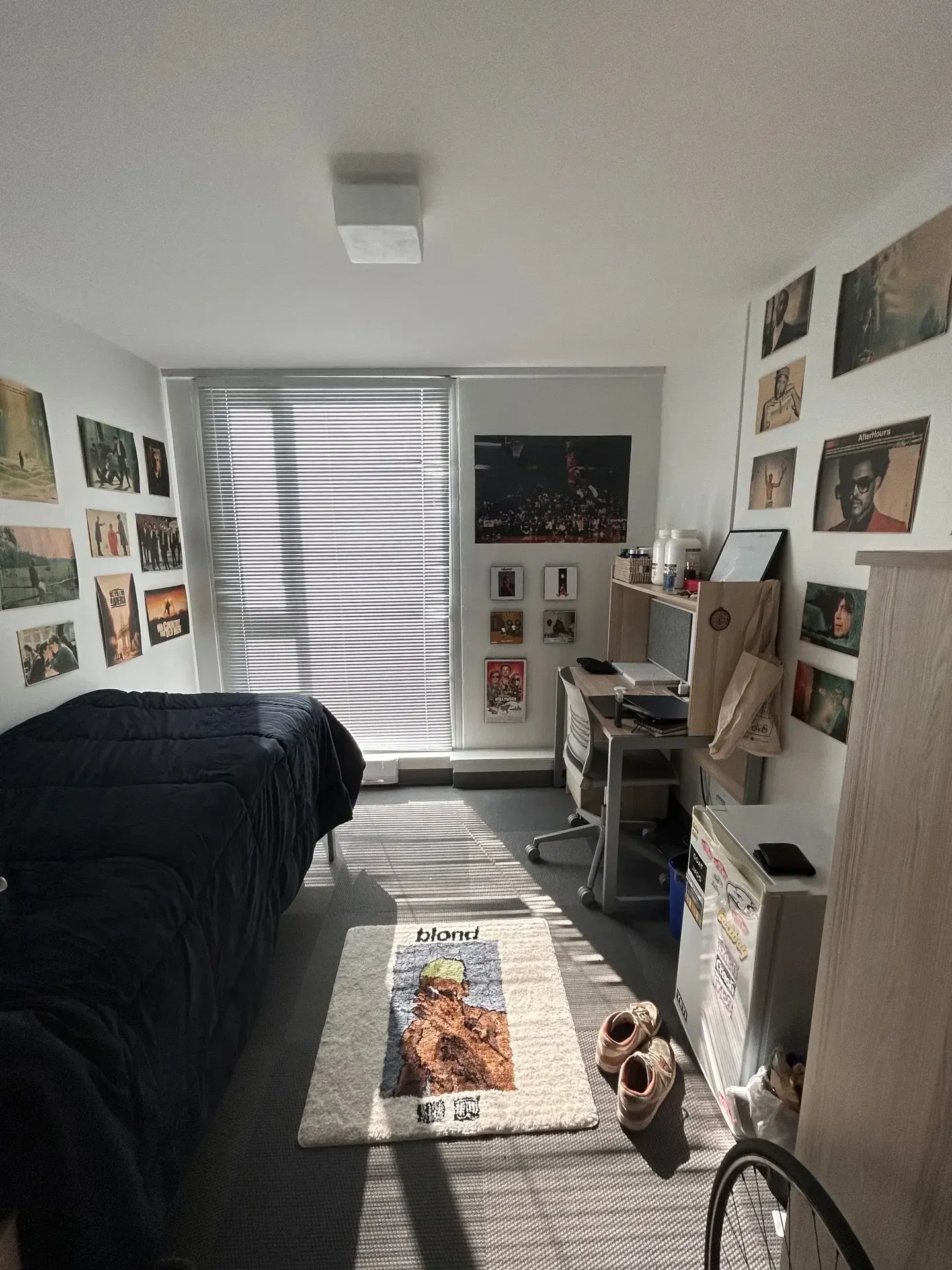 dorm decorating ideas for guys with photo wall, black bedding, dorm desk, rug, and window