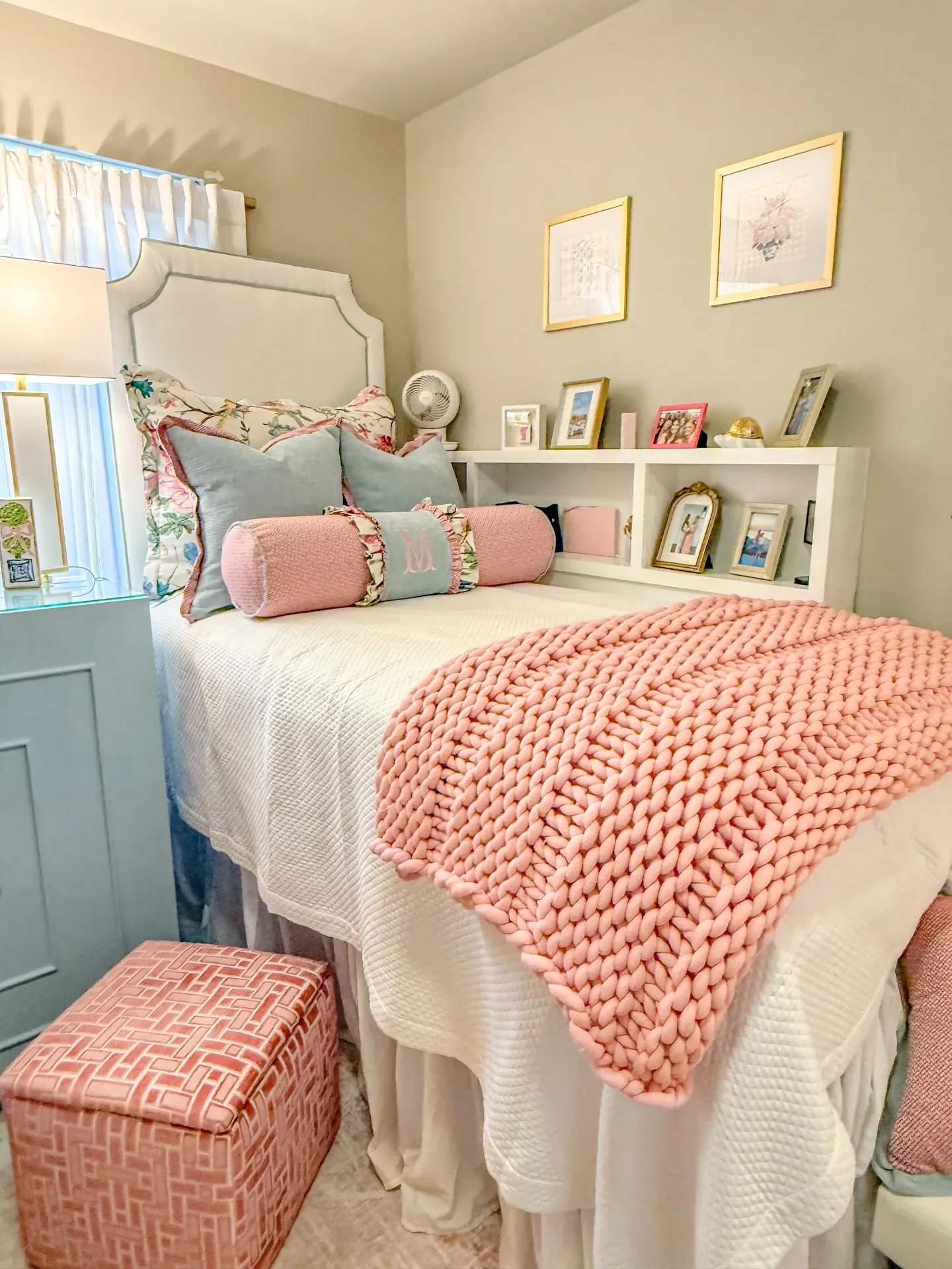 pink and blue dorm room ideas with pink throw blanket, blue pillows, lofted bed, white bedding, and shelf decor