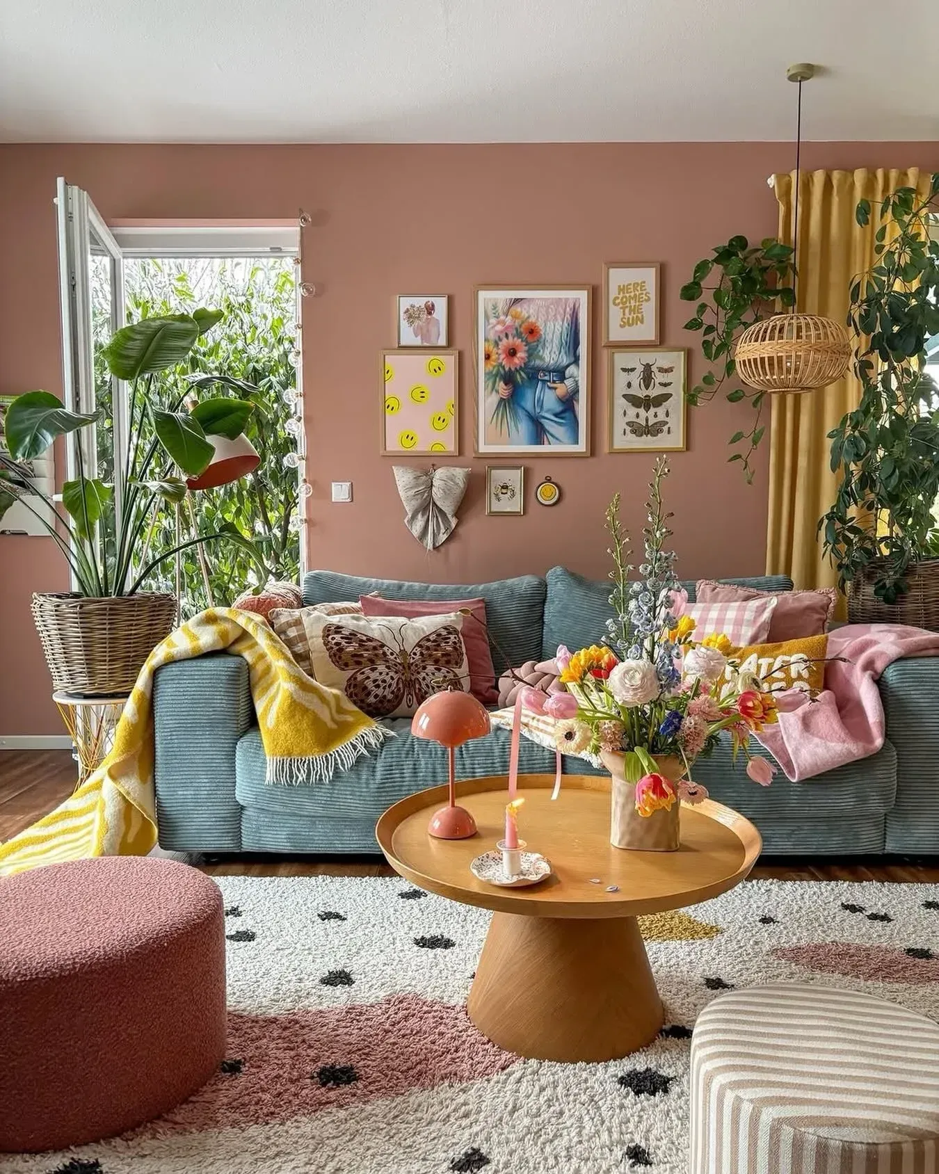 colorful living room ideas with pink walls, yellow curtains, green sofa, plants, gallery wall, and round coffee table