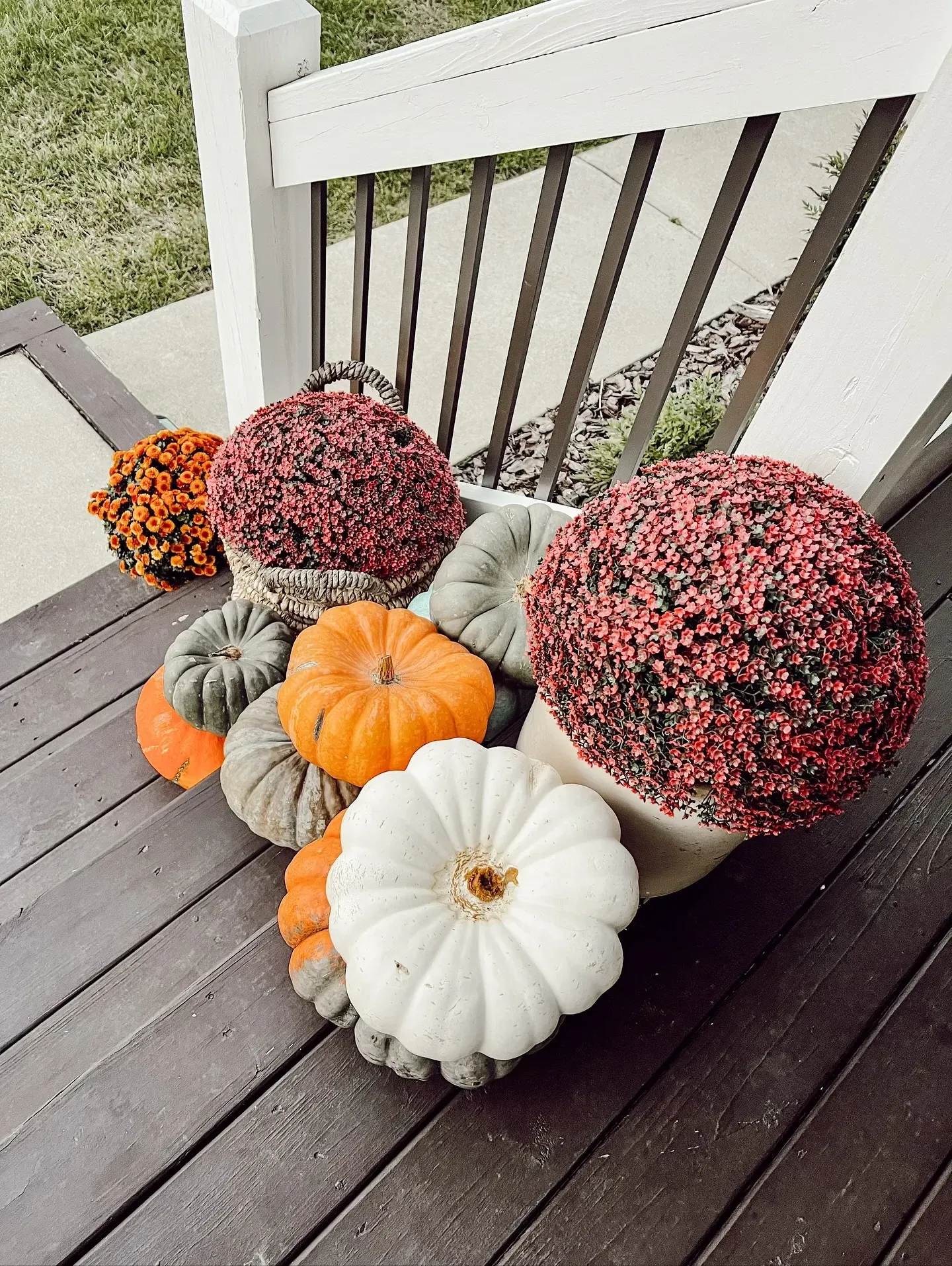 fall porch decor ideas with pink mums, orange mums, white pumpkins, green pumpkins, and a small porch corner