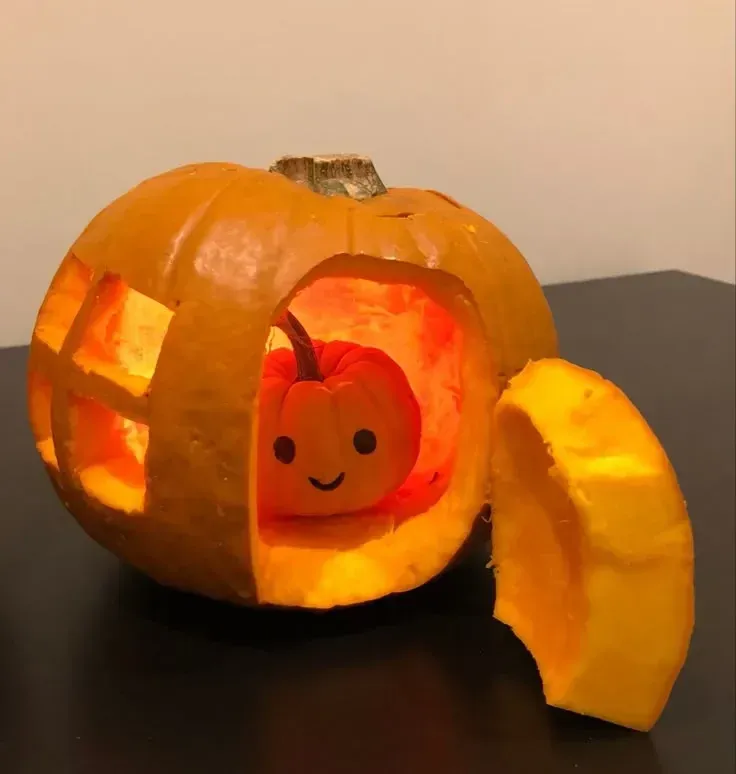 kid friendly pumpkin carving ideas with small pumpkin door, smiling face inside, and glowing cutout