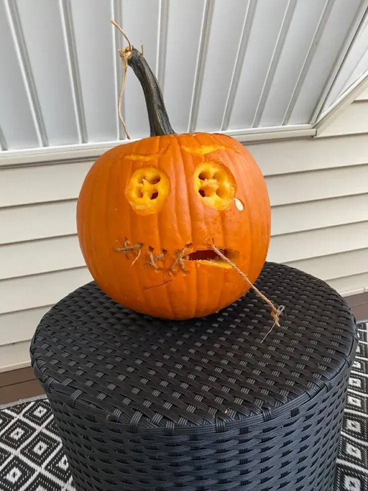 kid friendly pumpkin carving ideas with funny pumpkin face, twig hair, round eyes, and simple mouth