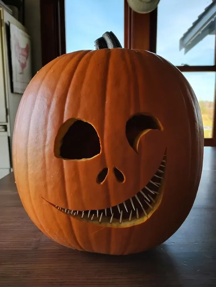 kid friendly pumpkin carving ideas with Jack Skellington pumpkin, large black eyes, stitched smile, and character design