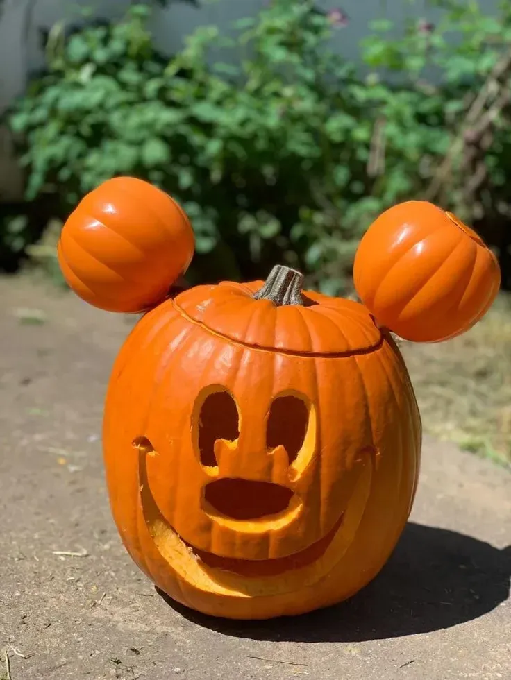 kid friendly pumpkin carving ideas with Mickey Mouse pumpkin, round ears, simple face, and glowing cutouts