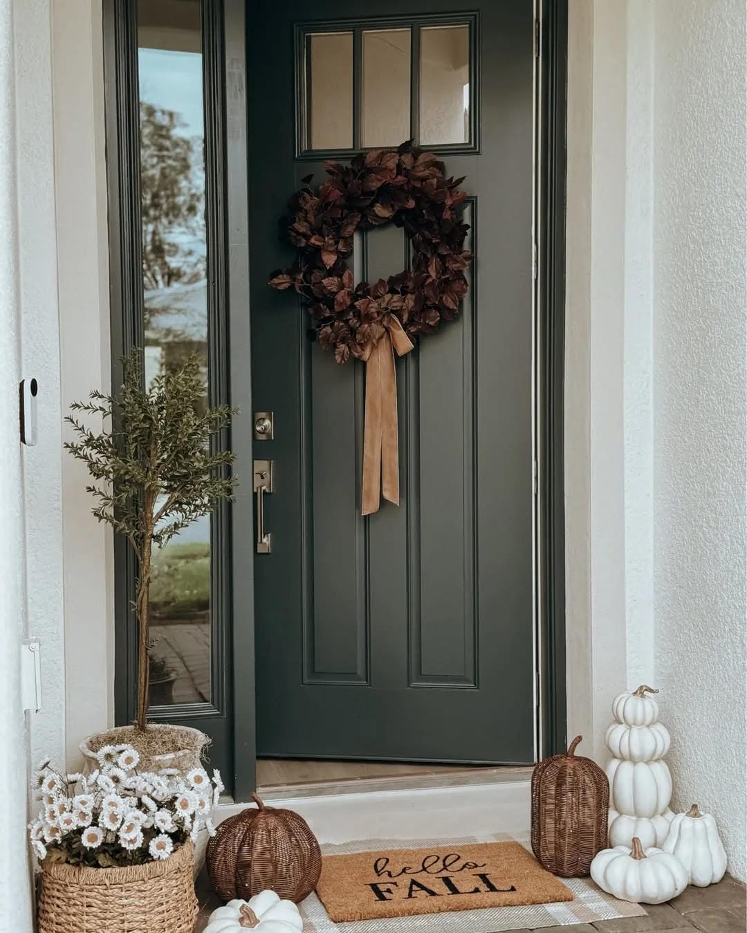 fall front door decor ideas with dark green door, wreath, pumpkins, white fall flowers, and hello fall doormat